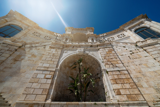 View of the Bastione di Saint Remy neoclassical stone facade with arches and columns under a bright sun flare and clear blue sky in Cagliari Sardegna Italy. View of the Bastione di Saint Remy neoclassical stone facade with arches and columns under a bright sun flare and clear blue sky in Cagliari Sardegna Italy.