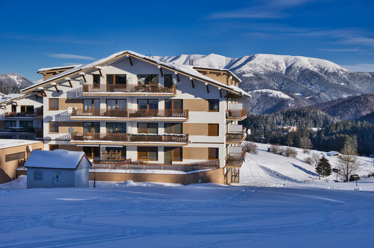 View of a multi story hotel with balconies stands out against the snow covered fields and distant majestic mountains under a clear blue sky Donovaly Banska Bystrica Region Slovakia. View of a multi story hotel with balconies stands out against the snow covered fields and distant majestic mountains under a clear blue sky Donovaly Banska Bystrica Region Slovakia.