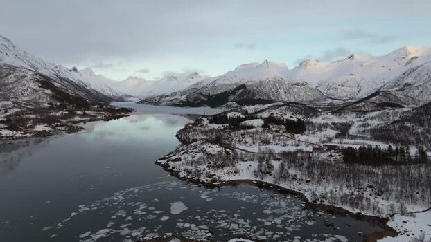 Aerial view of Lofoten snowy mountains and icy waters Norway.