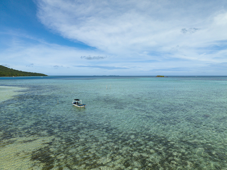 Aerial view of the turquoise waters meet the sky a lone boat sailing gently near Bobby Beach Karimunjawa Central Java Indonesia.