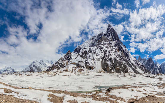 View of Mitre Peak with its sharp snow covered summit rising above the glacier under a blue sky with white clouds in Skardu Gilgit Pakistan.