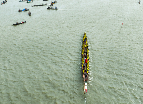 Baghabari Rajshahi Division Bangladesh 20 August 2022 Aerial view of a long boat race on the river featuring a large vessel with many rowers in yellow shirts.