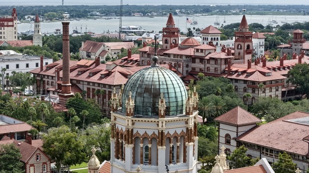 Aerial view of the ornate copper dome of the Memorial Presbyterian Church surrounded by historic red roofed buildings and lush greenery in St. Augustine Florida United States.
