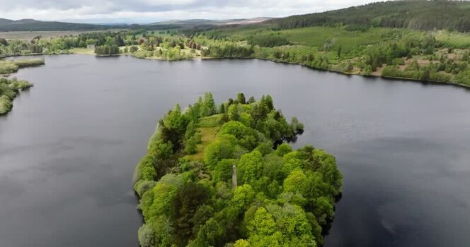 Aerial view of a forested island on a calm lake United Kingdom. Aerial view of a forested island on a calm lake United Kingdom.