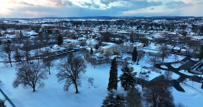 Aerial view of the snow covered town featuring historic buildings bare trees and a park landscape under a winter sky in Lititz Pennsylvania United States.