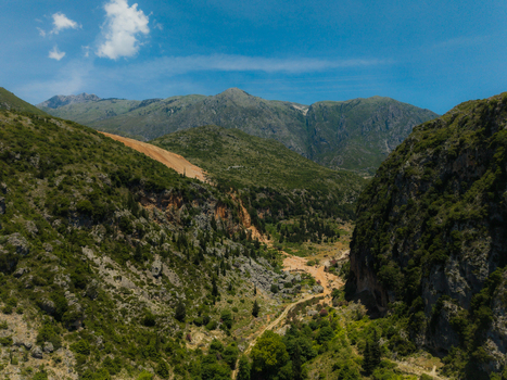 Aerial view of a deep mountain valley with lush green vegetation and rocky cliffs under a clear blue sky in Dhermi Vlore County Albania. Aerial view of a deep mountain valley with lush green vegetation and rocky cliffs under a clear blue sky in Dhermi Vlore County Albania.