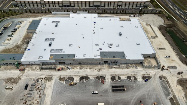 Aerial view of a large commercial warehouse under construction with a white flat roof and heavy machinery on site in World Golf Village Florida United States.