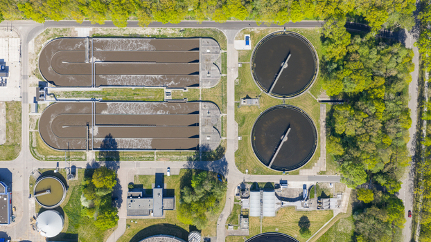Aerial view of RWZI Echten wastewater treatment plant with circular aeration tanks and rectangular basins surrounded by lush green trees in Hoogeveen Drenthe Netherlands. Aerial view of RWZI Echten wastewater treatment plant with circular aeration tanks and rectangular basins surrounded by lush green trees in Hoogeveen Drenthe Netherlands.