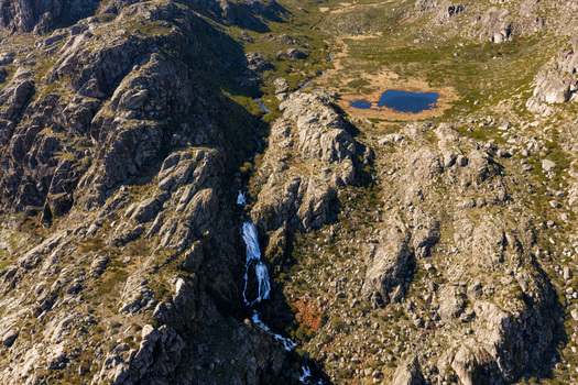 Aerial view of Vale da Candeeira with its waterfall and small blue lake nestled among the rugged granite cliffs of Serra da Estrela in Manteigas Distrito da Guarda Portugal. Aerial view of Vale da Candeeira with its waterfall and small blue lake nestled among the rugged granite cliffs of Serra da Estrela in Manteigas Distrito da Guarda Portugal.