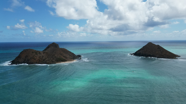 Aerial view of the tranquil turquoise waters surrounding the rugged dark islands under a bright scattered cloudscape Kailua Hawaii United States. Aerial view of the tranquil turquoise waters surrounding the rugged dark islands under a bright scattered cloudscape Kailua Hawaii United States.