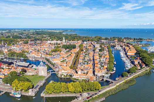 Aerial view of the historic town with its characteristic orange tiled rooftops canals and harbor surrounded by lush greenery in Enkhuizen North Holland Netherlands. Aerial view of the historic town with its characteristic orange tiled rooftops canals and harbor surrounded by lush greenery in Enkhuizen North Holland Netherlands.