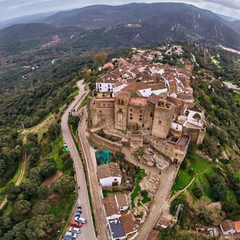 Aerial view of the historic Castellar de la Frontera castle perched atop a hill its weathered stone walls contrasting with the verdant landscape Castellar de la Frontera Andalusia Spain. Aerial view of the historic Castellar de la Frontera castle perched atop a hill its weathered stone walls contrasting with the verdant landscape Castellar de la Frontera Andalusia Spain.