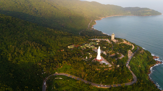 Aerial view of the Linh Ung Pagoda featuring the giant Lady Buddha statue surrounded by lush green forests and coastal roads overlooking the sea in Da Nang Vietnam. Aerial view of the Linh Ung Pagoda featuring the giant Lady Buddha statue surrounded by lush green forests and coastal roads overlooking the sea in Da Nang Vietnam.