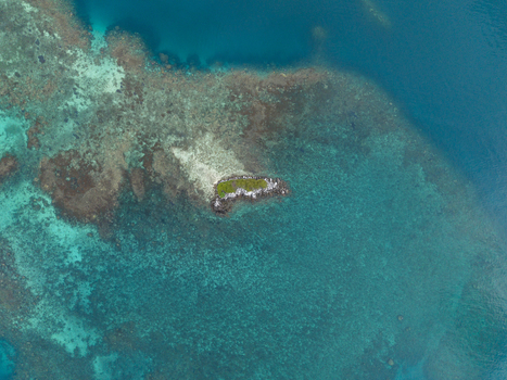 Aerial view of a small island surrounded by coral reefs in the turquoise waters of the ocean at Camar Rock Island Jepara Regency Central Java Indonesia.