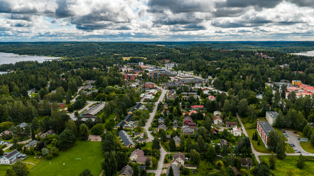 Aerial view of the town of Asikkala featuring residential houses lush green forests and the distant lake under a cloudy sky Asikkala Paijat Hame Finland.