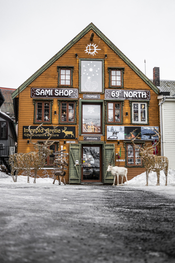 Tromso Norway 11 March 2026 View of the traditional wooden facade of a Sami souvenir shop decorated with reindeer figures and lights in the snowy city center. Tromso Norway 11 March 2026 View of the traditional wooden facade of a Sami souvenir shop decorated with reindeer figures and lights in the snowy city center.