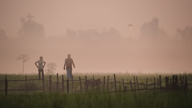 View of people in a misty rural field in Bogura Bangladesh.