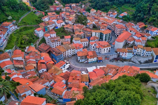 Aerial view of the colorful houses and red tiled roofs of the historic fishing village nestled in a lush green valley Cudillero Asturias Spain. Aerial view of the colorful houses and red tiled roofs of the historic fishing village nestled in a lush green valley Cudillero Asturias Spain.