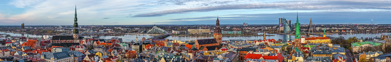 Aerial view of the historic Old Town of Riga with its iconic church spires red tiled rooftops and the Daugava River flowing past the modern city skyline in Riga Latvia.