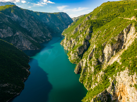 Aerial view of Piva Lake with its deep turquoise waters winding through steep rocky canyon walls and lush green slopes in Pluzine Municipality Montenegro. Aerial view of Piva Lake with its deep turquoise waters winding through steep rocky canyon walls and lush green slopes in Pluzine Municipality Montenegro.
