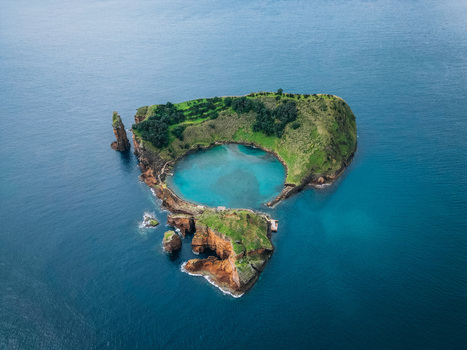 Aerial view of an islet with lush green vegetation and a serene blue lagoon surrounded by deep blue waters Vila Franca do Campo Azores Portugal.
