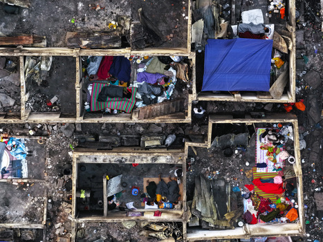 Aerial view of Korail Basti showing makeshift shelters with people resting on mats and blankets amidst debris and urban poverty in Dhaka Dhaka Division Bangladesh.