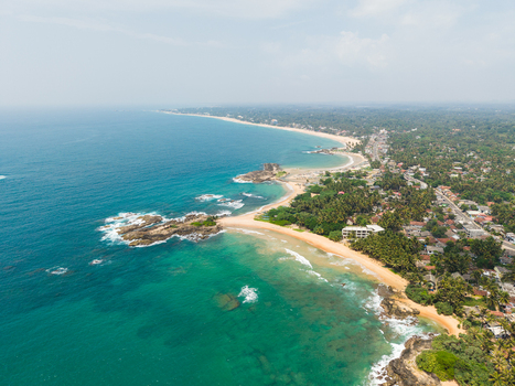 Aerial view of the tropical coastline with sandy beaches turquoise ocean water and lush palm trees in Dodanduwa Southern Province Sri Lanka. Aerial view of the tropical coastline with sandy beaches turquoise ocean water and lush palm trees in Dodanduwa Southern Province Sri Lanka.
