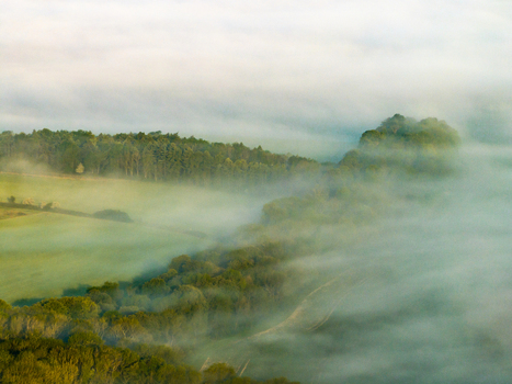 Aerial view of the rolling green hills and dense forests shrouded in thick morning mist in Nuffield Oxfordshire United Kingdom. Aerial view of the rolling green hills and dense forests shrouded in thick morning mist in Nuffield Oxfordshire United Kingdom.