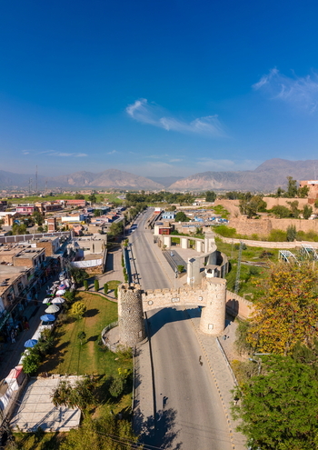 Aerial view of the historic Khyber Pass stone gateway spanning the road with surrounding mountains and clear blue sky in Khyber District Khyber Pakhtunkhwa Pakistan. Aerial view of the historic Khyber Pass stone gateway spanning the road with surrounding mountains and clear blue sky in Khyber District Khyber Pakhtunkhwa Pakistan.