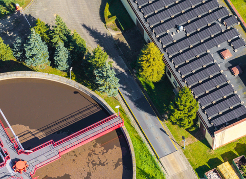 Aerial view of wastewater treatment plant with solar panels installed on the roof surrounded by green trees and industrial infrastructure in Pomeranian Voivodeship Poland. Aerial view of wastewater treatment plant with solar panels installed on the roof surrounded by green trees and industrial infrastructure in Pomeranian Voivodeship Poland.