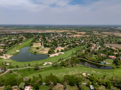 Ahmedabad India 21 March 2026 Aerial view of Kalhaar Blues Greens Golf Club featuring lush fairways sand bunkers and water hazards surrounded by villas and trees.