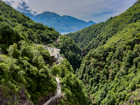 Aerial view of Verzasca Dam infrastructure surrounded by dense green forests and steep mountain slopes overlooking Lake Maggiore Gordola Ticino Switzerland. Aerial view of Verzasca Dam infrastructure surrounded by dense green forests and steep mountain slopes overlooking Lake Maggiore Gordola Ticino Switzerland.