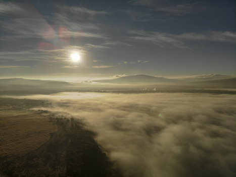 Aerial view of a landscape covered in thick morning fog with the sun rising over distant hills in Tonala Jalisco Mexico. Aerial view of a landscape covered in thick morning fog with the sun rising over distant hills in Tonala Jalisco Mexico.