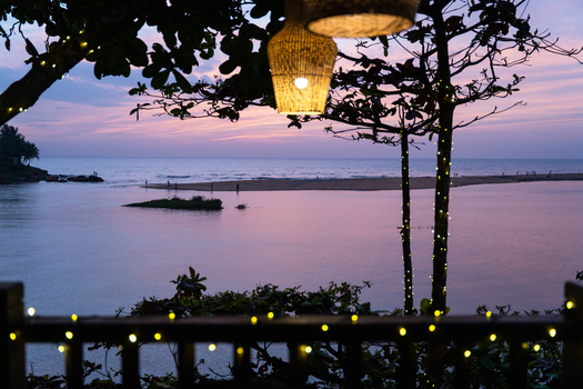 View of a tranquil river lagoon at sunset with hanging wicker lamps and fairy lights on trees in Galle Southern Province Sri Lanka.