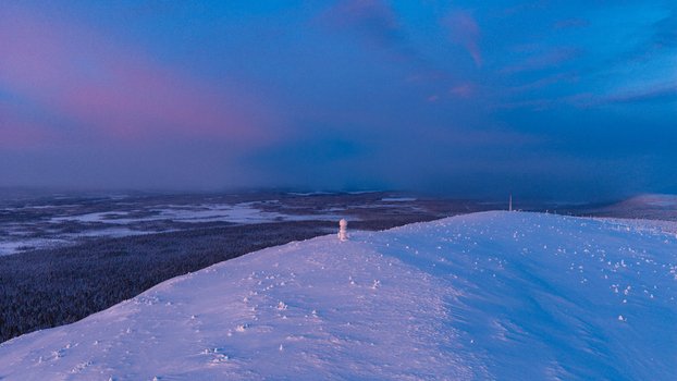 Aerial view of Luosto fell with snow covered trees and a vast winter landscape under a colorful twilight sky in Sodankyla Lapland Finland. Aerial view of Luosto fell with snow covered trees and a vast winter landscape under a colorful twilight sky in Sodankyla Lapland Finland.