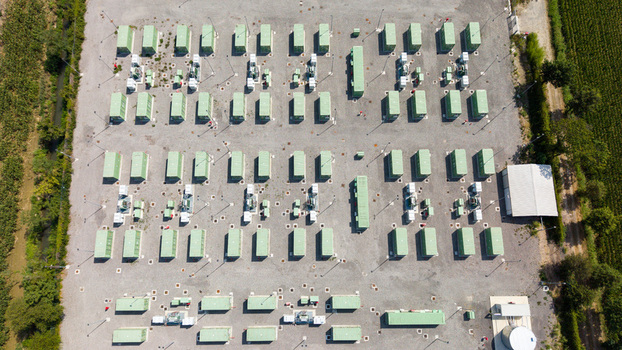 Aerial view of a modern battery energy storage system with rows of green containers and power equipment on a gravel site in Tavazzano con Villavesco Lombardy Italy.