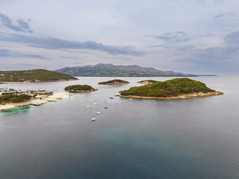 Aerial view of the Ksamil islands surrounded by turquoise waters small boats and lush greenery along the coastline in Ksamil Vlore County Albania. Aerial view of the Ksamil islands surrounded by turquoise waters small boats and lush greenery along the coastline in Ksamil Vlore County Albania.