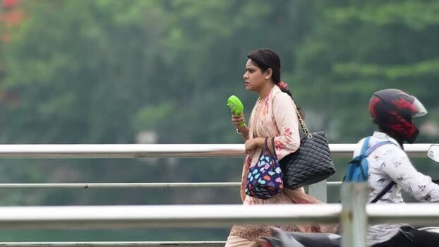 View of a woman walking with a portable fan in Dhaka Bangladesh.
