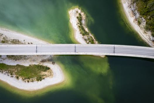 Aerial view of a bridge cutting across the Sylvensteinsee lake its stark concrete contrasting with the turquoise and emerald waters Sylvensteinspeicher Bayern Germany. Aerial view of a bridge cutting across the Sylvensteinsee lake its stark concrete contrasting with the turquoise and emerald waters Sylvensteinspeicher Bayern Germany.