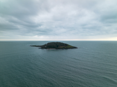 Aerial view of Looe Island surrounded by the calm sea under a cloudy sky in Looe Cornwall United Kingdom. Aerial view of Looe Island surrounded by the calm sea under a cloudy sky in Looe Cornwall United Kingdom.