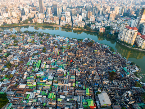 Aerial view of a vibrant mix of informal settlements and modern high rises divided by a river creating a striking contrast between old and new Dhaka Dhaka Division Bangladesh. Aerial view of a vibrant mix of informal settlements and modern high rises divided by a river creating a striking contrast between old and new Dhaka Dhaka Division Bangladesh.