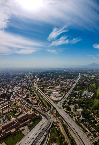 Aerial view of the historic Bala Hisar Fort surrounded by urban sprawl modern highway infrastructure and green spaces in Peshawar Khyber Pakhtunkhwa Pakistan.