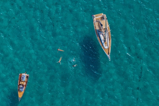 Aerial view of Ile Sainte Marguerite featuring a sailboat and a smaller motorboat anchored in clear turquoise water with people swimming nearby in Cannes Provence Alpes Cote d Azur France. Aerial view of Ile Sainte Marguerite featuring a sailboat and a smaller motorboat anchored in clear turquoise water with people swimming nearby in Cannes Provence Alpes Cote d Azur France.
