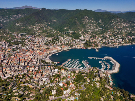 Aerial view of the harbor filled with yachts coastal buildings and lush green hills under a clear blue sky Rapallo Liguria Italy. Aerial view of the harbor filled with yachts coastal buildings and lush green hills under a clear blue sky Rapallo Liguria Italy.