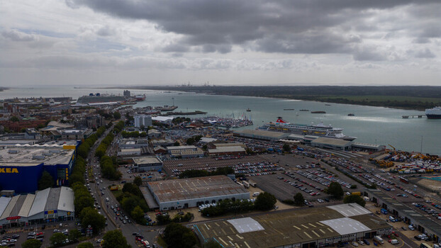 Aerial view of the port of Southampton with cruise ships docked at the terminal parking lots and industrial warehouses under a cloudy sky in Southampton England United Kingdom. Aerial view of the port of Southampton with cruise ships docked at the terminal parking lots and industrial warehouses under a cloudy sky in Southampton England United Kingdom.