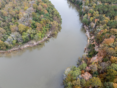 Aerial view of a tranquil river winding through a tapestry of autumnal trees showcasing nature s vibrant palette Fort Motte South Carolina United States.