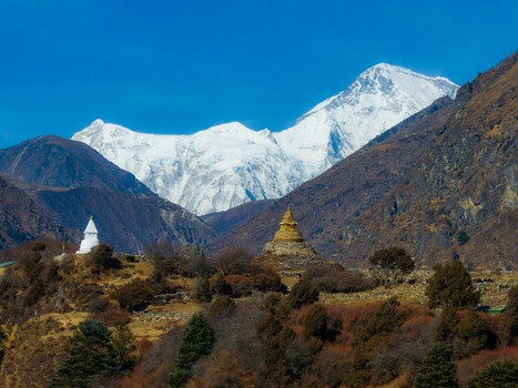 Aerial view of Buddhist stupas set against the snow capped Himalayan mountains in Nepal.