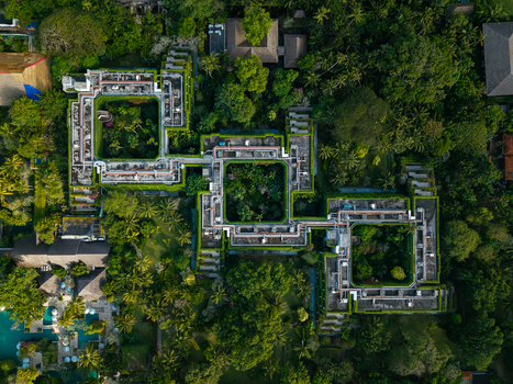 Aerial view of a luxury resort complex featuring interconnected square buildings with central courtyards lush tropical gardens and a swimming pool in Kecamatan Denpasar Selatan Bali Indonesia. Aerial view of a luxury resort complex featuring interconnected square buildings with central courtyards lush tropical gardens and a swimming pool in Kecamatan Denpasar Selatan Bali Indonesia.