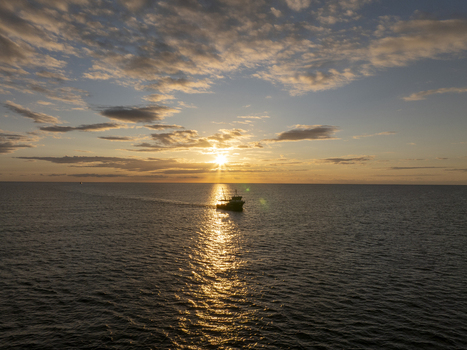 Aerial view of a fishing boat sailing on the calm sea during a golden sunset near the historic town of Nessebar Burgas Bulgaria. Aerial view of a fishing boat sailing on the calm sea during a golden sunset near the historic town of Nessebar Burgas Bulgaria.