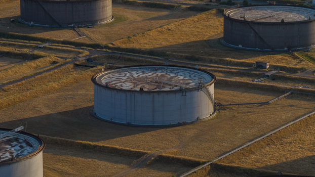 Aerial view of Tanklager oil storage tanks situated in a grassy field during golden hour in Hunxe North Rhine Westphalia Germany.